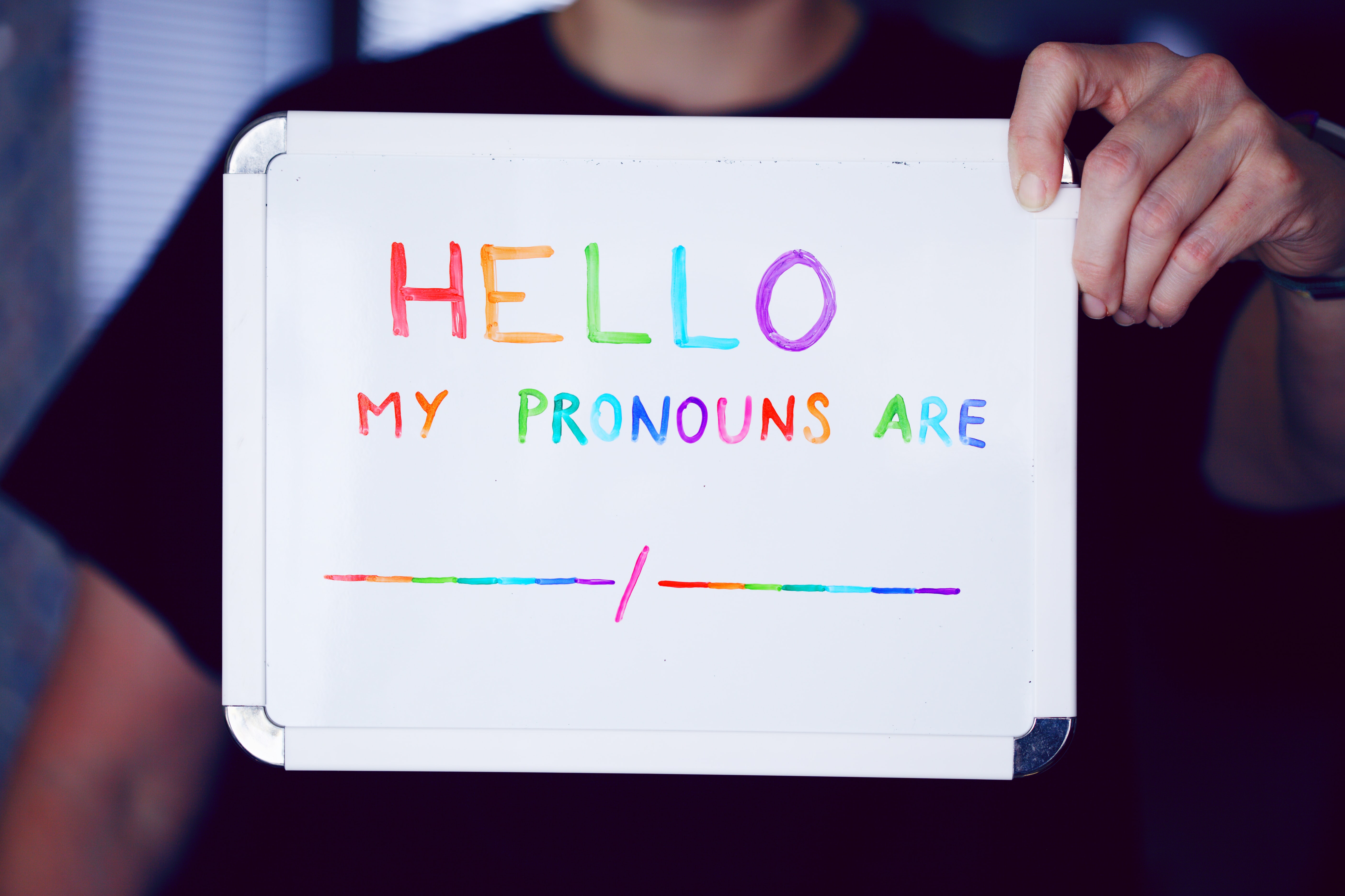 White board with, "Hello. My pronouns are [blank]," in a rainbow ink. 