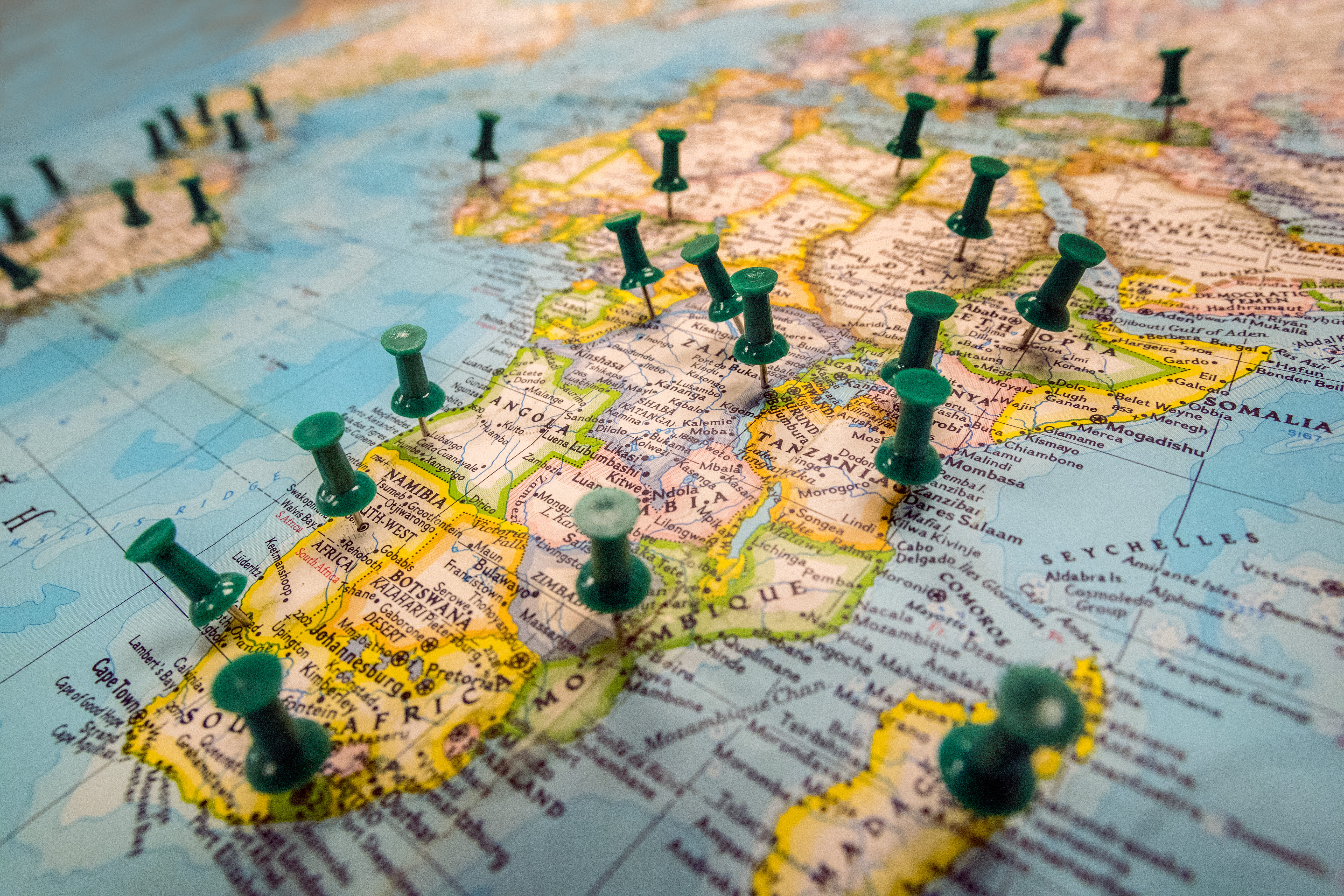 Detail photo of a map focused on the continent of Africa with green push pins marking various cities across the globe